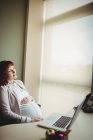 Pregnant businesswoman touching belly in office — Stock Photo