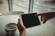 Main de femme en utilisant une tablette numérique dans le café — Photo de stock