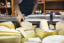 Secção média do pessoal feminino que trabalha no balcão de queijos no supermercado — Fotografia de Stock