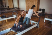 Instructor assisting a woman while practicing pilates in fitness studio — Stock Photo