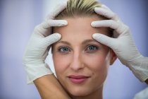 Mãos de médico examinando rosto paciente feminino para tratamento cosmético — Fotografia de Stock