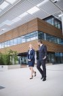 Geschäftsmann läuft mit Kollege vor dem Eingang eines Bürogebäudes — Stockfoto