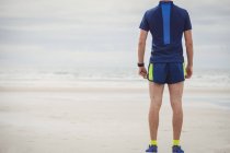 Вид ззаду спортсмена, що стоїть на піщаному пляжі — стокове фото