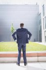 Вид ззаду бізнесмена, що стоїть руками на стегні поза офісною будівлею — стокове фото