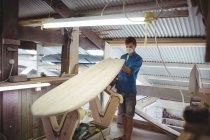Мужчина делает доску для серфинга в интерьере мастерской — стоковое фото