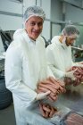 Retrato de açougueiros embalando salsichas cruas na fábrica de carne — Fotografia de Stock
