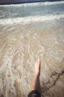 Низкая часть женщины, идущей по пляжу в воде — стоковое фото