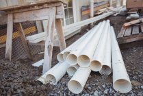 Plastic pipes and wooden planks at construction site — Stock Photo