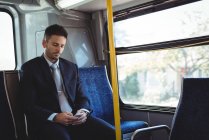 Businessman using mobile phone while travelling in the bus — Stock Photo