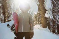 Woman standing and holding a snowboard on snow covered mountain — Stock Photo