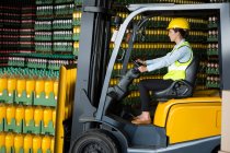 Side view of confident female worker driving forklift in warehouse — Stock Photo
