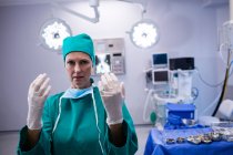 Portrait of female surgeon wearing surgical gloves in operation theater of hospital — Stock Photo
