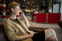 Бізнес-леді розмовляє по мобільному телефону в зоні очікування в терміналі аеропорту — стокове фото