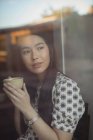 Donna premurosa che ha una tazza di caffè vicino alla finestra al caffè — Foto stock