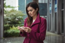 Beautiful businesswoman using phone on street — Stock Photo