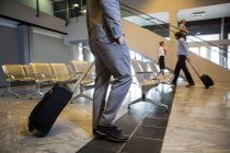 Пасажири, які ходять з багажем у зоні очікування в аеропорту — стокове фото
