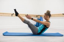 Mujer realizando ejercicio de estiramiento en gimnasio - foto de stock