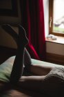 Baixa seção de mulher deitada na cama no quarto — Fotografia de Stock