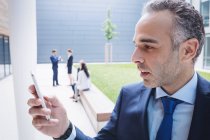 Бізнесмен використовує мобільний телефон за межами офісної будівлі — стокове фото
