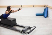 Mujer ejercitándose en reformador en gimnasio - foto de stock