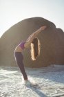 Femme effectuant du yoga sur la plage à la journée ensoleillée — Photo de stock