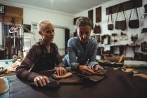 Ремесленницы готовят кожаный чехол для мобильного телефона в мастерской — стоковое фото