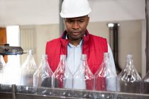 Serious male employee examining bottles in juice factory — Stock Photo