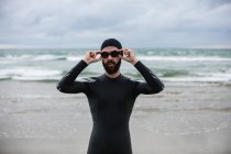 Atleta in muta che indossa occhiali da nuoto sulla spiaggia — Foto stock