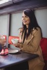Женщина держит чашку кофе и смотрит на мужчину за столом кафе — стоковое фото
