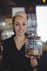 Ritratto di cameriera con barattolo di biscotti al bancone nel caffè — Foto stock