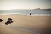 Vue arrière de la femme debout sur la plage pendant la journée — Photo de stock