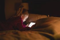Девушка сидит с помощью цифрового планшета в спальне дома — стоковое фото