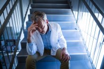 Trauriger Arzt sitzt im Krankenhaus auf Treppe — Stockfoto
