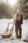 Female musher standing beside sleigh on a snowy landscape — Stock Photo