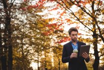 Empresário usando tablet digital enquanto toma suco no outono — Fotografia de Stock