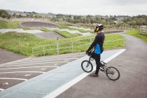Cycliste debout avec BMX vélo sur la rampe de départ au skatepark — Photo de stock