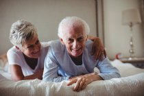 Happy senior couple lying on bed in bed room — Stock Photo