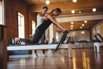 Coach aider une femme tout en pratiquant pilates dans un studio de fitness — Photo de stock