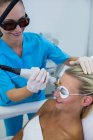 Woman receiving laser epilation treatment on forehead at beauty salon — Stock Photo