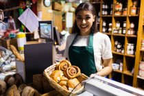 Female staff holding croissant in wicker basket at bread counter in supermarket — Stock Photo