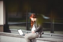 Беременная деловая женщина с ноутбуком в офисных помещениях — стоковое фото