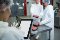 Primo piano della tecnica femminile con tablet digitale in fabbrica di carne — Foto stock