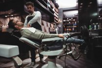 Barbiere mettere asciugamano sopra il cliente in negozio di barbiere — Foto stock