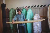 Мужчина выбирает доску для серфинга в мастерской — стоковое фото