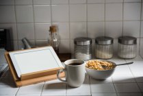 Comprimido digital e café da manhã na bancada da cozinha em casa — Fotografia de Stock