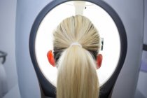 Mujer recibiendo escaneo láser estético en clínica, vista trasera - foto de stock