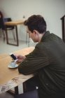 Side view of man using his phone while sitting in coffee shop — Stock Photo