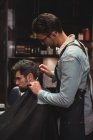 Man getting hair trimmed by hairdresser with razor in barber shop — Stock Photo