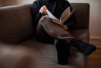 Человек читает книгу в гостиной дома — стоковое фото