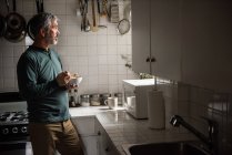 Вдумчивый мужчина завтракает дома на кухне — стоковое фото